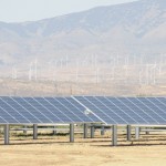 Solar panels with wind turbines in background